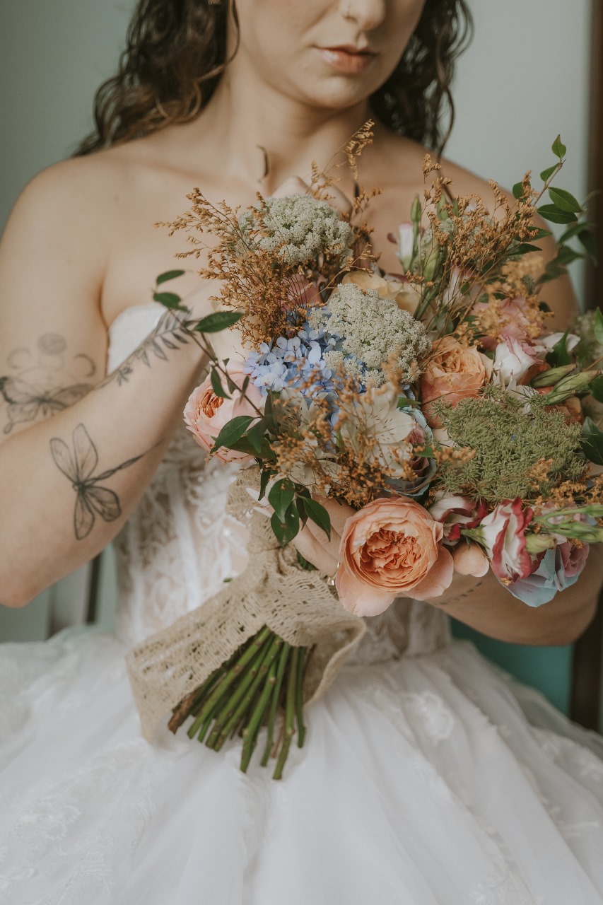 Arco de casamento com rosas brancas e folhagens sobre caminho de pétalas