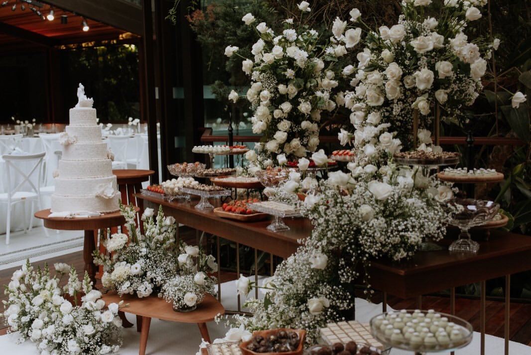 Mesa de doces de casamento com arranjos de rosas brancas e mosquitinho